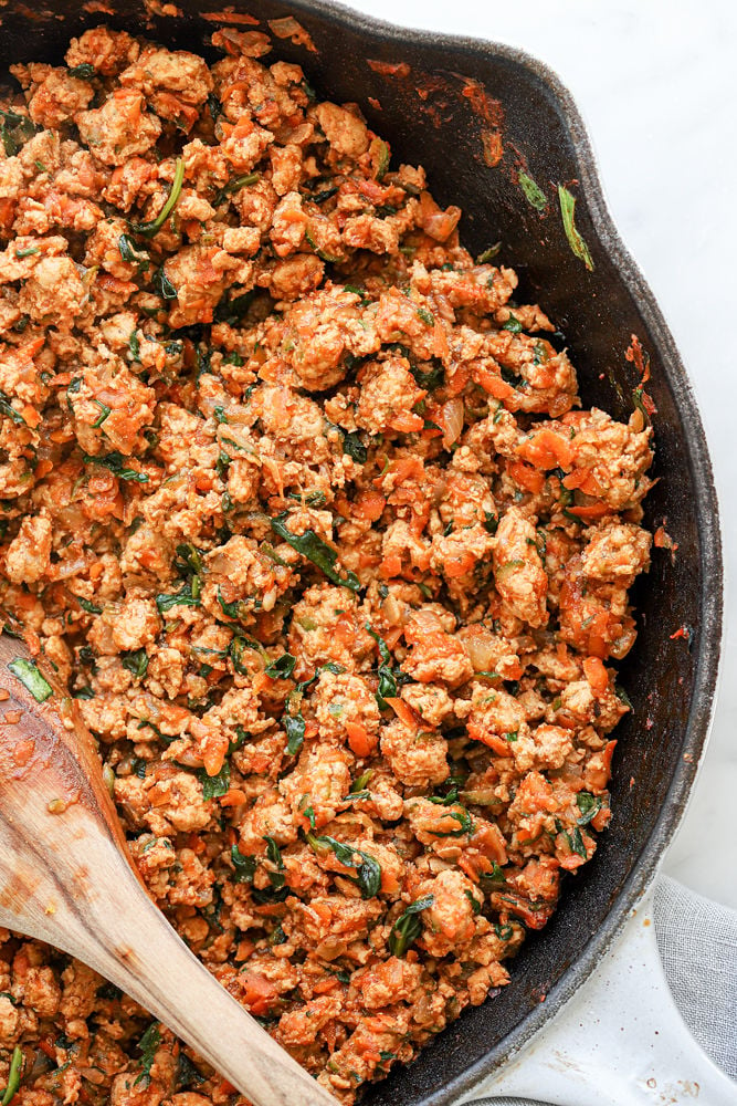Veggie-Loaded turkey sloppy joe mixture in a skillet with a wooden spoon after being cooked. 