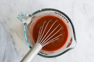 Sauce for sloppy joes in a measuring cup with a whisk