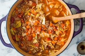 Cooked unstuffed cabbage soup in a pot with a wooden spoon.