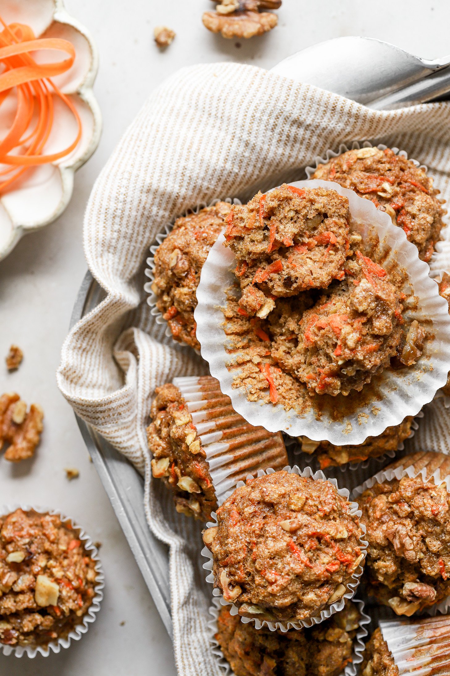 A basket of carrot oatmeal muffins. The top muffin is split in two to show the texture inside. 