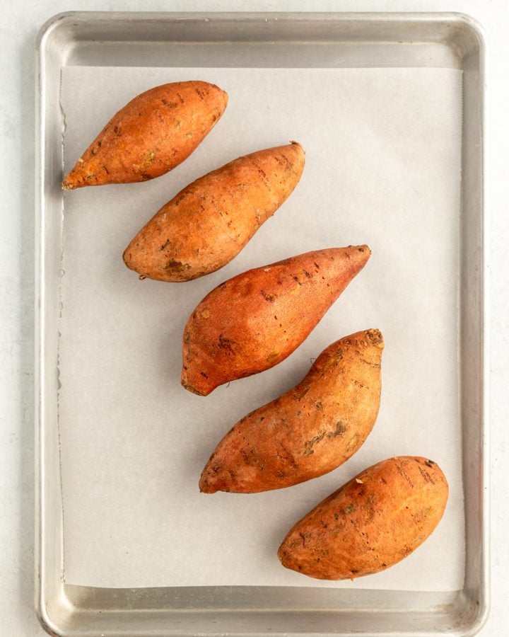 Washed and prepped sweet potatoes on a lined baking sheet before baking. 