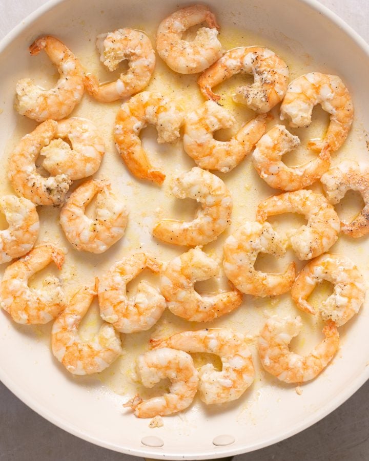 Cooked shrimp in a white skillet.