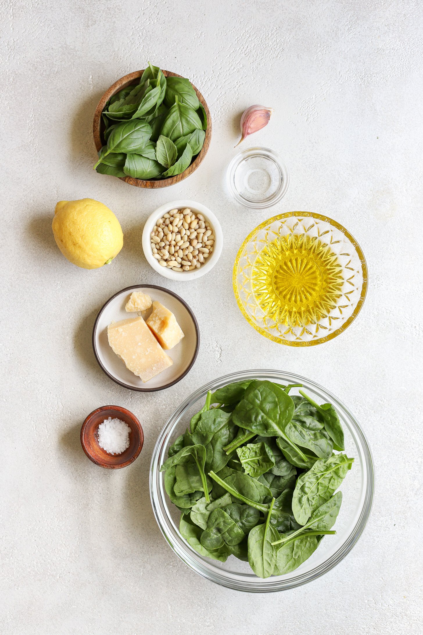 Ingredients for spinach pesto on a table in bowls.