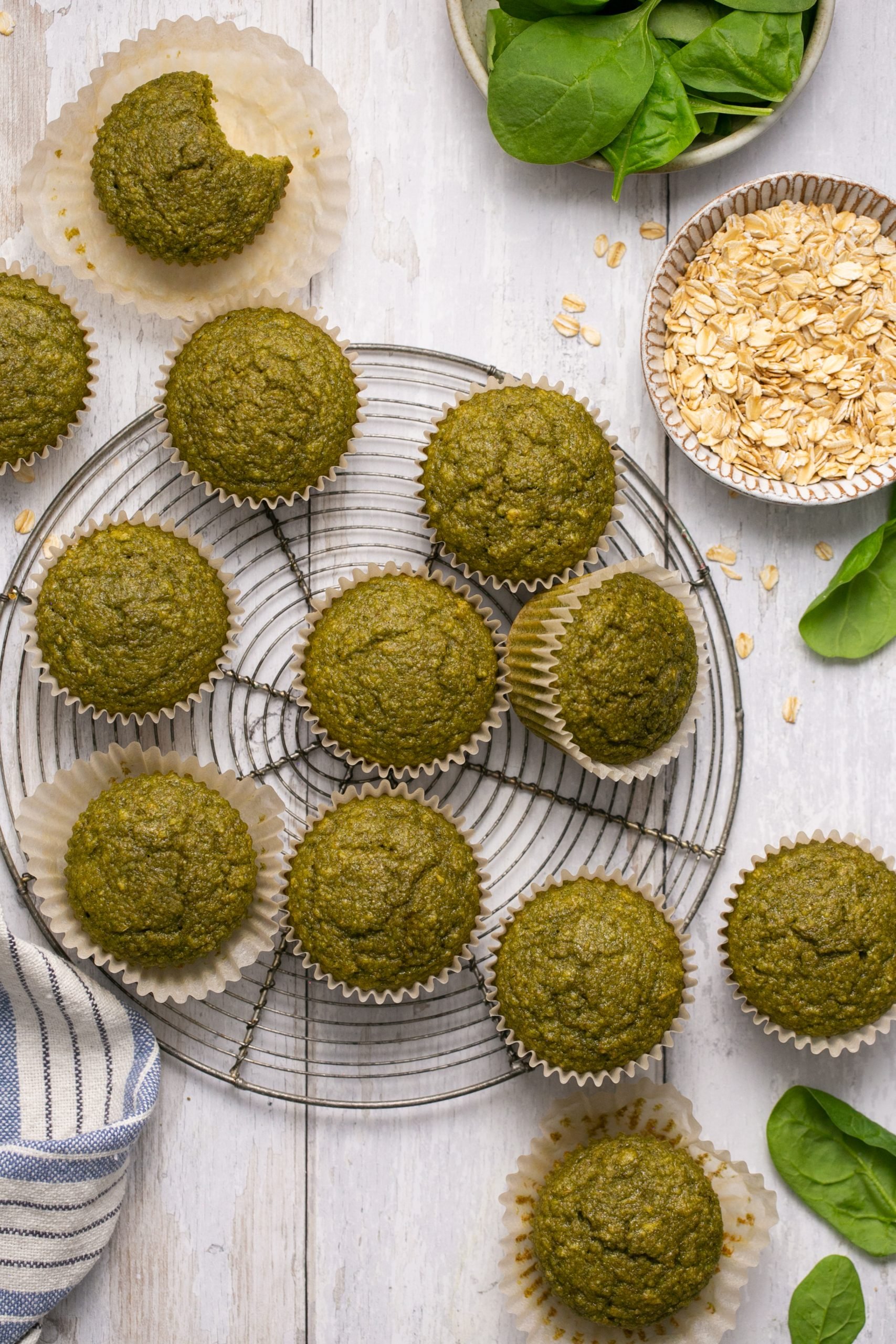 Green smoothie muffins on a round cooling rack with bowls of ingredients surrounding them 