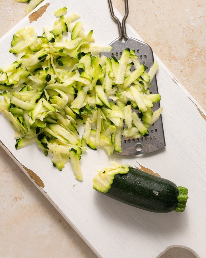 Zucchini grated on a cutting board with metal grater