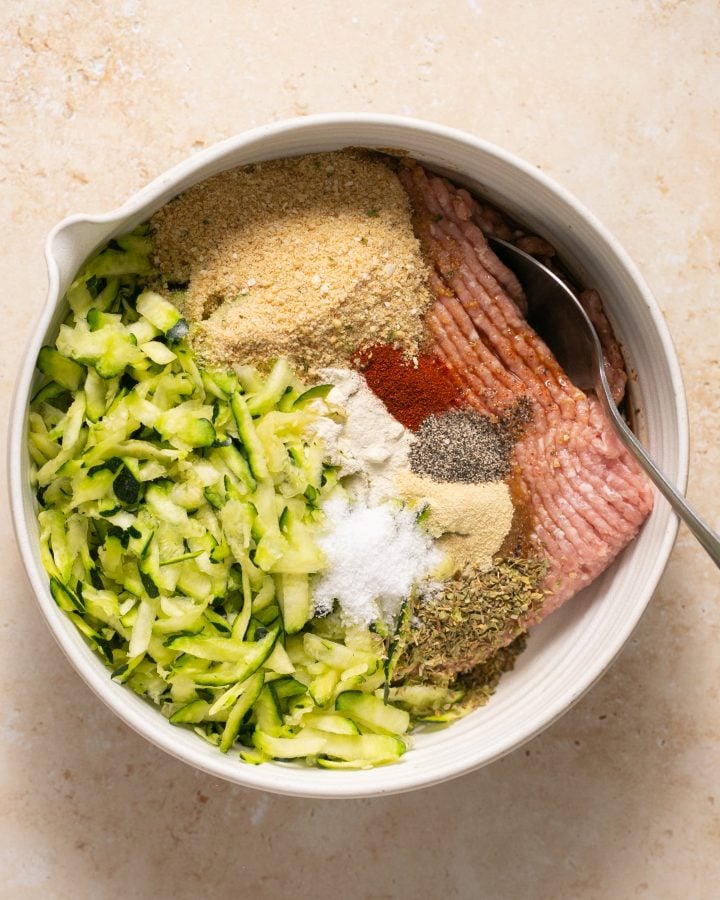 The ingredients for turkey zucchini burgers in a large mixing bowl before being mixed together. 