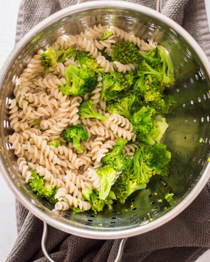 Cooked broccoli florets and pasta in a strainer