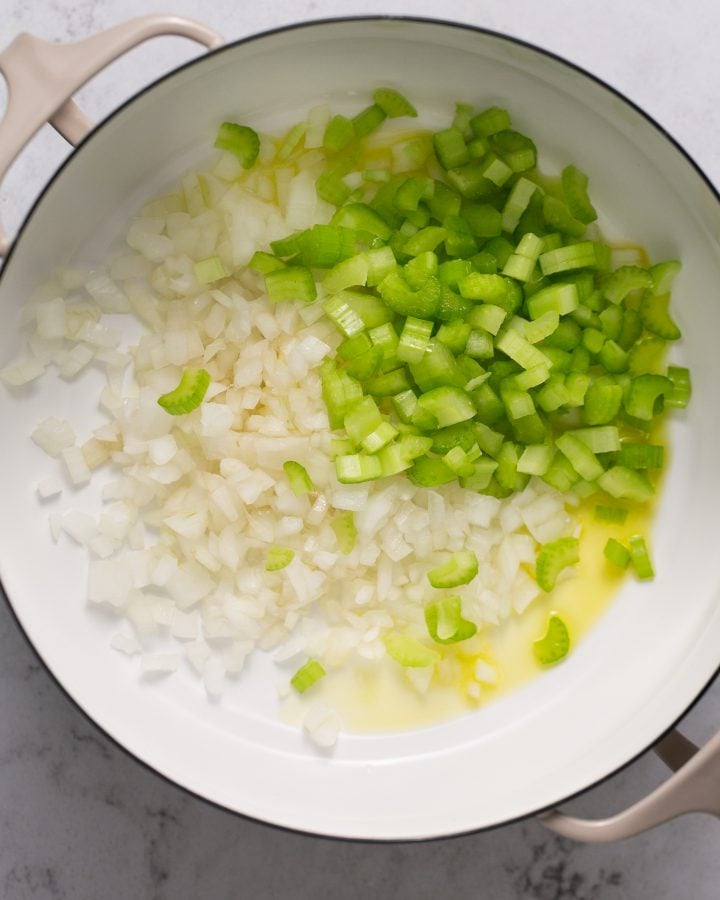 Diced celery and onions in a white Dutch oven with melted butter and oil 