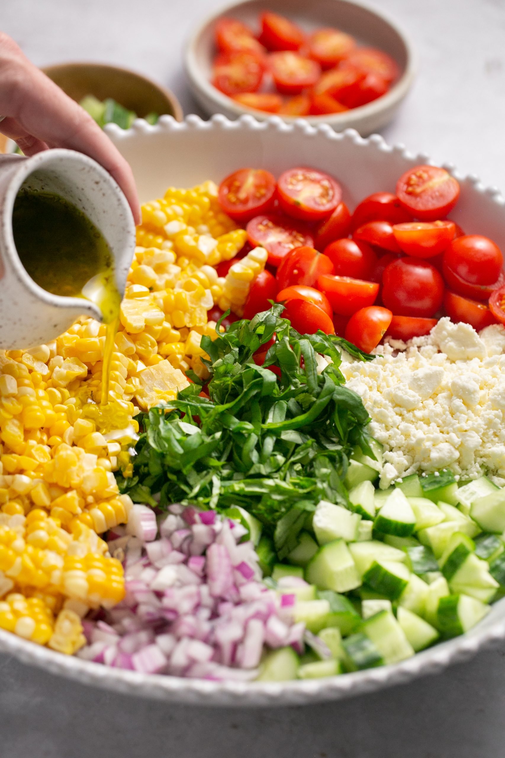 Hand pouring dressing over the other ingredients for the Quick & Fresh Corn Salad.