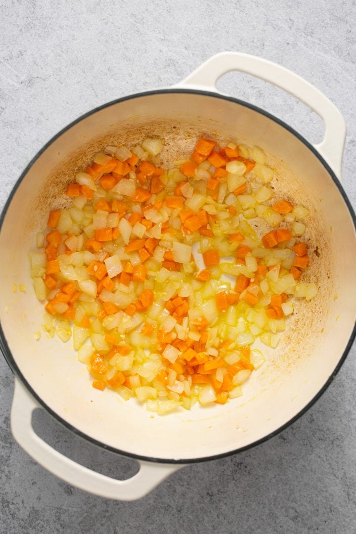 Onions and carrots sauteed in a Dutch oven with oil