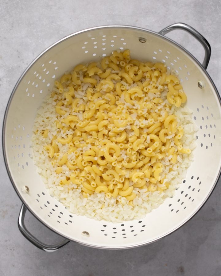 Cooked elbow pasta and riced cauliflower in a strainer.