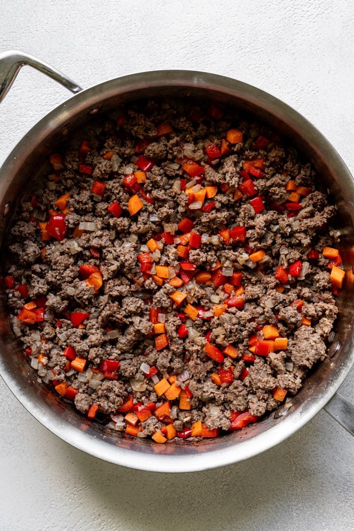 Cooked ground beef in a pot with carrots, bell peppers and onions.