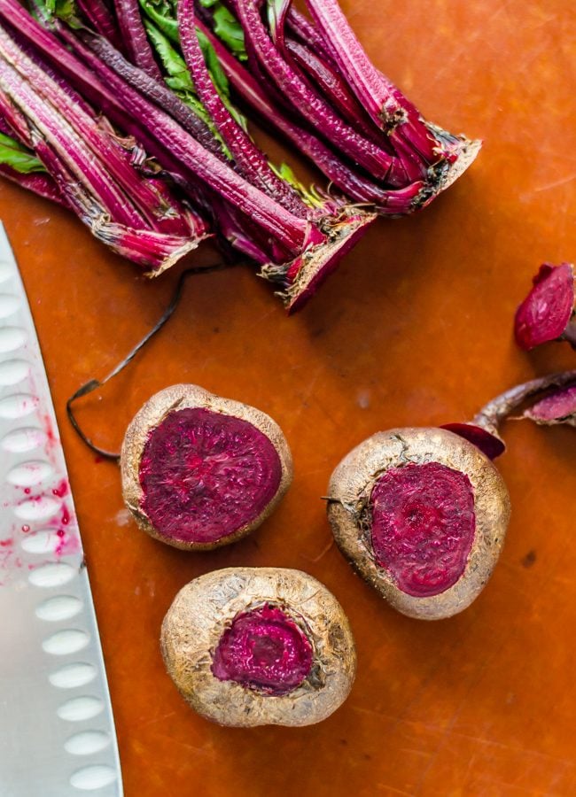 Beets on a cutting board with their tops and roots cut off. 