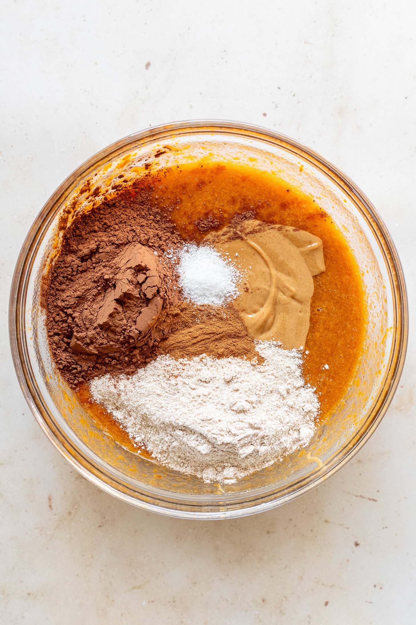 Dry ingredients and peanut butter in a bowl with the wet ingredients before being mixed in.
