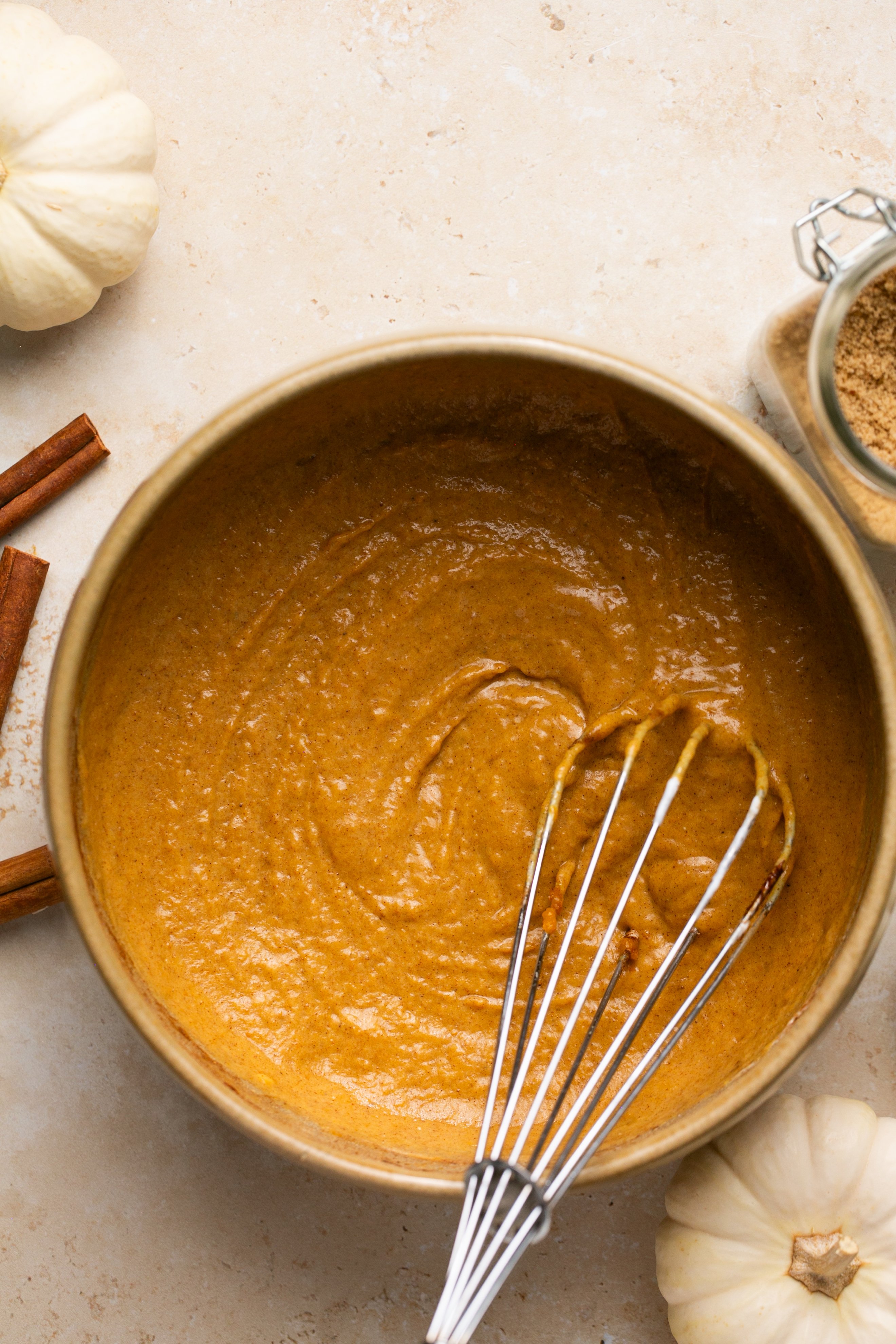 Wet ingredients for pumpkin pancakes mixed together in a bowl with a whisk.